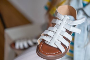 Beyaz sandaletli küçük çocuk ayakları, ayakkabı giymeyi öğrenme, bebek bağımsızlığı, çocukluk gelişimi, tatlı yaz anı, kendini giydirme becerisi, parti ya da özel etkinliğe hazır olmak, çocukluk sevinci