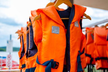 Parlak turuncu can yelekleri asılı, güvenlik ekipmanları su sporları, yaz etkinlikleri hazırlığı, su güvenliği, macera ve yaz tatili, su sporları için uygun can yelekleri, açık hava eğlence ekipmanları