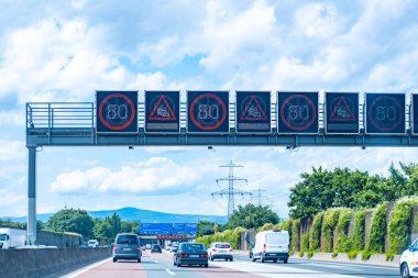 Alman otoban elektronik tabelaları hız limiti 80, trafik sıkışıklığı uyarısı, otomobiller hızla hareket eden Avrupa otoyol ağı, yaz yolculuğu günü, Frankfurt - 15 Temmuz 2025
