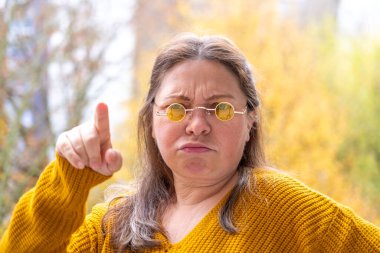 Kızgın olgun kadın tartışıyor, suçluyor, sinirli duygusal agresif jest, suçlama duygusu, üzgün orta yaşlı kadın yakın çekim görüşü, çatışma, duygusal patlamalar, vücut dili.