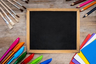 Okul malzemeleri, okula dönüş kavramları veya yaratıcı öğrenme, okul veya sanat atölyesi, çizim ve yazma araçları, elle eğitim, öğrenci yazma malzemeleri ile çevrili karatahta