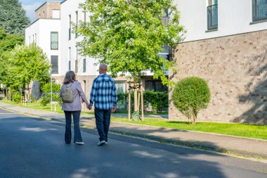 Modern binanın önünde kendine güvenen mutlu, olgun bir çift, sarı şapkalı kadın, ofis binasının yanındaki adam, Avrupa iş mimarisi, kentsel geçmiş. 