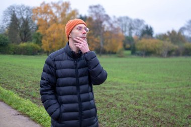 Doğada huzurlu bir anın tadını çıkaran bir adam sonbaharda günlük kıyafetlerini giyer, doğa düzeninde modaya uygun erkek modeller, kırsal alanda yürüyüş veya yürüyüş yapar, modern yaşam tarzı portreleri çizer. 