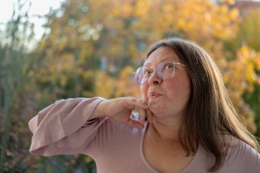 Şok olmuş, şaşırmış olgun bir kadın akıllı telefonunu tutar ve geniş gözleriyle duygusal tepki verir, şok içinde ekrana bakar. Beklenmedik haberlere duygusal tepki, virüs içeriği, beklenmedik online olay 