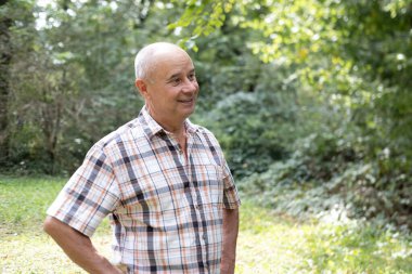 Mutlu, beyaz, olgun bir adam, 60-65 yaşlarında, yeşil doğal arka planda gülümseyen, iyi ruh hali, yaşla ilgili değişiklikler, insan sağlığı kavramı, yetişkinlikte iyimserlik.