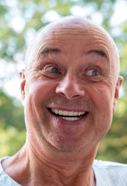 Mutlu, beyaz, olgun bir adam, 60-65 yaşlarında, yeşil doğal arka planda gülümseyen, iyi ruh hali, yaşla ilgili değişiklikler, insan sağlığı kavramı, yetişkinlikte iyimserlik.