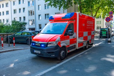Alman itfaiye minibüsünde mavi ışıklar, şehir caddesinde park etmiş acil ambulans, itfaiye, kırmızı kurtarma aracı, tıbbi müdahale, Frankfurt, Almanya - 26 Temmuz 2025