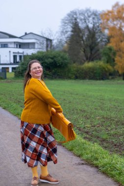 Doğal yaşam tarzı portresi gözlüklü neşeli kadın dışarıda yürümekten hoşlanıyor, aynı sarı aksesuarlar, özgün vücut pozitifliği, kırsal yaşam tarzı mutluluğu.