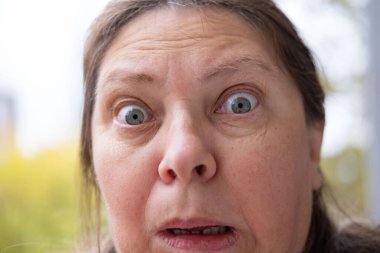 Dramatik bir portre. Şaşırmış bir kadın, şoke olmuş, gözleri açık, şişkin, inançsız ve beklenmedik haberler veren, inançsızlıkla ve şaşkınlıkla donmuş, duygusal bir yüzle bakıyor.