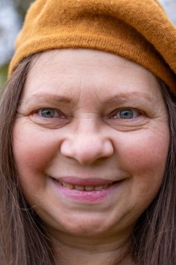 Gülümseyen orta yaşlı kadın uzun saçlı, kendini beğenmiş, kendine güvenen, doğal yaşlanma, pozitif ruh hali, yakın görüş, açık hava ışığı, sağlıklı yaşam tarzı, yakın yüz görünümü, sağIık teması 