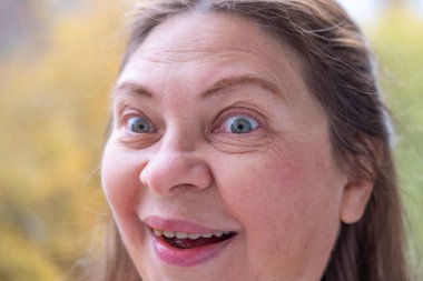 Gülümseyen orta yaşlı kadın uzun saçlı, kendini beğenmiş, kendine güvenen, doğal yaşlanma, pozitif ruh hali, yakın görüş, açık hava ışığı, sağlıklı yaşam tarzı, yakın yüz görünümü, sağIık teması 