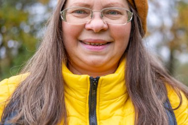 Gülümseyen orta yaşlı kadın uzun saçlı, kendini beğenmiş, kendine güvenen, doğal yaşlanma, pozitif ruh hali, yakın görüş, açık hava ışığı, sağlıklı yaşam tarzı, yakın yüz görünümü, sağIık teması 