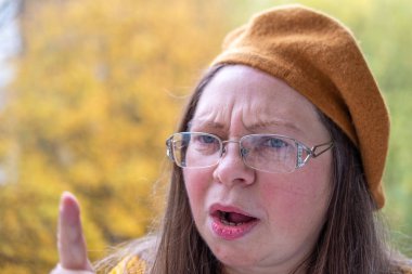 Kuşkucu olgun kadın açık havada, kadın yüzü hayal kırıklığını, şüpheciliği ve duygusal acıyı gösteriyor. Yakın plan, hayal kırıklığını ve şüpheyi gergin bir pozla ifade eden kadın modeli. 