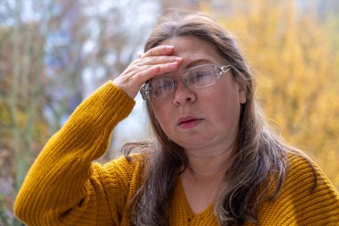 Kuşkucu olgun kadın açık havada, kadın yüzü hayal kırıklığını, şüpheciliği ve duygusal acıyı gösteriyor. Yakın plan, hayal kırıklığını ve şüpheyi gergin bir pozla ifade eden kadın modeli. 