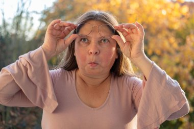 Kuşkucu olgun kadın açık havada, kadın yüzü hayal kırıklığını, şüpheciliği ve duygusal acıyı gösteriyor. Yakın plan, hayal kırıklığını ve şüpheyi gergin bir pozla ifade eden kadın modeli. 