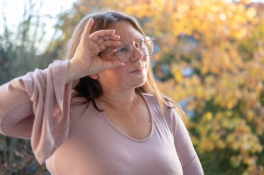 Kuşkucu olgun kadın açık havada, kadın yüzü hayal kırıklığını, şüpheciliği ve duygusal acıyı gösteriyor. Yakın plan, hayal kırıklığını ve şüpheyi gergin bir pozla ifade eden kadın modeli. 