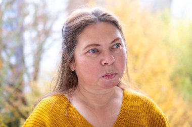 Kuşkucu olgun kadın açık havada, kadın yüzü hayal kırıklığını, şüpheciliği ve duygusal acıyı gösteriyor. Yakın plan, hayal kırıklığını ve şüpheyi gergin bir pozla ifade eden kadın modeli. 