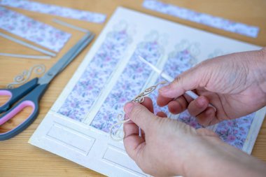 Eller detaylandırılmış dekupaj DIY projesi için çiçek kağıtlarını titizlikle kesiyor, iş yerinde hobici, rahatlatıcı ve yaratıcı zanaat faaliyetlerine girişiyor.
