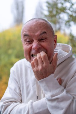 Mutlu, beyaz, olgun bir adam, 60-65 yaşlarında, yeşil doğal arka planda gülümseyen, iyi ruh hali, yaşla ilgili değişiklikler, insan sağlığı kavramı, yetişkinlikte iyimserlik. 