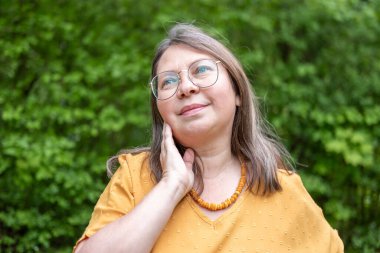 Şaşırmış, orta yaşlı, açık havada uzun saçlı bir kadın, şok olmuş bir yetişkin portresi, stres, hayat sorunları, yüz ifadesi. Şok, şaşkınlık ve beklenmedik duygular konsepti 