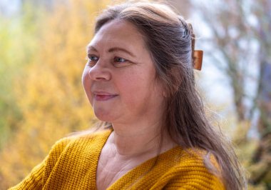 Şaşırmış, orta yaşlı, açık havada uzun saçlı bir kadın, şok olmuş bir yetişkin portresi, stres, hayat sorunları, yüz ifadesi. Şok, şaşkınlık ve beklenmedik duygular konsepti 