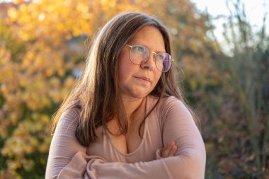 Şaşırmış, orta yaşlı, açık havada uzun saçlı bir kadın, şok olmuş bir yetişkin portresi, stres, hayat sorunları, yüz ifadesi. Şok, şaşkınlık ve beklenmedik duygular konsepti 