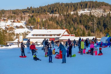 Kayakçılar ve snowboardcular, karlı dağ yamacındaki kış tatilinde yokuş aşağı yarışıyorlar. İnsanlar hızlı kayak yapıyor. Tatil macerası, turizm, kayak kültürü, Gerardmer, Fransa - 27 Aralık 2024 