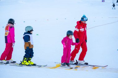 Kayakçılar ve snowboardcular, karlı dağ yamacındaki kış tatilinde yokuş aşağı yarışıyorlar. İnsanlar hızlı kayak yapıyor. Tatil macerası, turizm, kayak kültürü, Gerardmer, Fransa - 27 Aralık 2024 