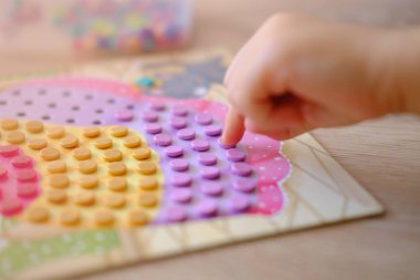 Küçük roller çocuğun elinde, kız mozaikle oynuyor, boşlukları dolduruyor, motor becerilerini geliştiriyor, erken öğrenim aktiviteleri, eğitici oyun zamanı