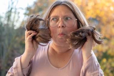 50 'li yaşlardaki kadınlar vitamin eksikliği ve yaşlanma nedeniyle kırılgan ve hasarlı saçları, incelmeyi ve kuruluğu inceliyor. Olgun kadınlarda trichology yardımı, sağlık hizmetleri için yaygın olan gerçekçi tasvir saç sorunları.