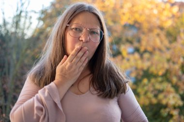 Şaşırmış, orta yaşlı, açık havada uzun saçlı bir kadın, şok olmuş bir yetişkin portresi, stres, hayat sorunları, yüz ifadesi. Şok, şaşkınlık ve beklenmedik duygular konsepti