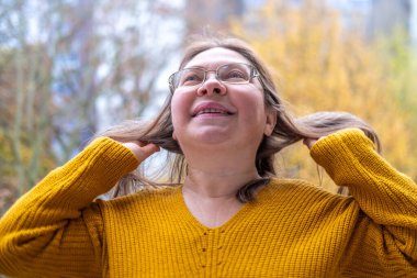 Kendine güvenen, orta yaşlı, 55 yaşında, uzun saçlı, doğal güzelliği kucaklayan, kendine güvenen, kendine güvenen, iç huzuru ve güveni olan, zamansız kadınsı bir kadın. 