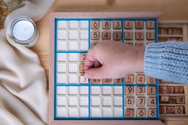 Kadınların ellerini dikkatlice Sudoku bulmacası içine yerleştirirken, meydan okuyan bulmacaları çözmeye kendini kaptırmış yaşlı insanlar, beyin sağlığı, zihinsel aktivite klasik oyunu