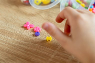 Çocuğun parmakları trafoları manipülatörle hareket ettirir, tasarımcı parçalarından monte edilir, bokeh ile yeşil arka plan, iyi motor becerilerin geliştirilmesi konsepti, yaratıcılık, çocuk eğlencesi 