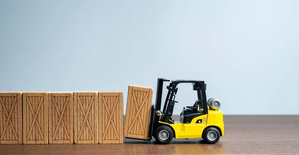 A forklift makes a fence wall out of wooden boxes. Mass production. Delivery of parcels and orders. Trading traffic. Transportation and transfer. Logistics. Delivery of oversized cargo.