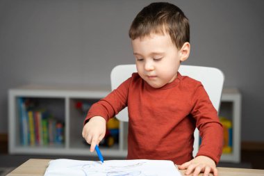 İki yaşında sevimli, küçük bir çocuk evde çocuk odasındaki albümde işaretlerle resim çiziyor. Çocuklar için eğitim faaliyetleri