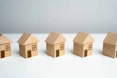 Tahta oyuncak evler sıraya dizilir. En uygun konut seçeneklerini bul. Emlak piyasasında teklif veriyor. İpotek. Konut binalarının değeri. Emlakçı servisi. Alış ve satım.