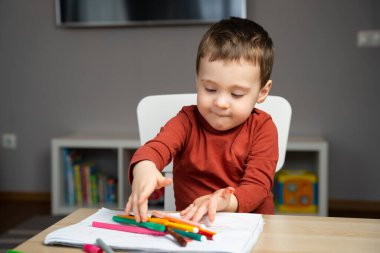 Evdeki çocuk odasında, albümdeki kalemlerle oynayan, iki yıllık mutlu, küçük bir çocuk. Çocuklar için eğitici aktiviteler. Seçici odak.