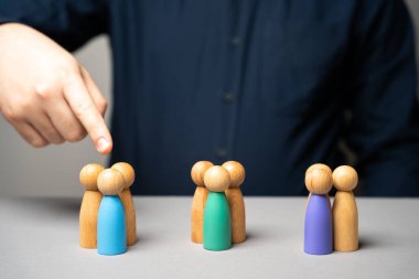 Piyasa segmentasyonu kavramı. Hedef kitle, müşteri hizmetleri. Alıcı pazarı. Müşteri ilişkileri yönetimi. İşadamı parmağını insanların ahşap heykellerine doğrultuyor.