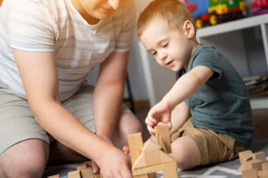 Küçük çocuk 2.5 yıl boyunca babasıyla tahta bloklar oynadı. Çocuklarla vakit geçirmek. Çocuklar için eğitici aktiviteler. Çocuk odası. İçeride. Seçici odak