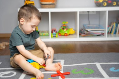 2,5 yaşında küçük bir çocuk oyuncak bir helikopterle oynuyor, onu monte ediyor ve parçalara ayırıyor. Çocuklar için eğitici oyuncaklar. Evde çocuk odası var. Kapalı