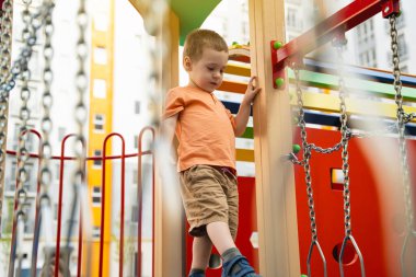 İki ya da üç yaşında tatlı bir çocuk, bir yerleşim yerinin bahçesinde oyun oynuyor. Çocuklar için sağlıklı bir yaz aktivitesi. Çocuk oyunları. Seçici odak