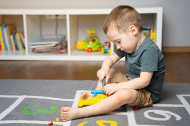 Küçük bir çocuk oyuncak bir helikopterle oynuyor, onu monte ediyor ve söküyor. Çocuklar için eğitici oyuncaklar. Evde çocuk odası var. Kapalı