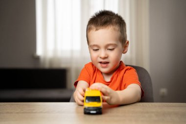 Oyuncak sarı bir arabayla oynayan tatlı bir çocuk. Çocuk eğlencesi ve yaşam tarzı. Çocukluk. Çocuğa odaklan..