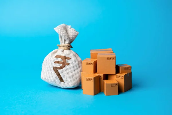 Goods boxes and indian rupee money bag. Budget purchases, large purchase orders. Global currency. Trade deal. Import and export. Profit from sales and production of goods, economic growth.