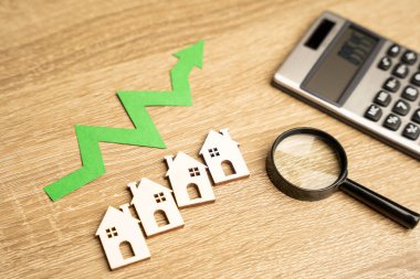 Minyatür evler, yukarı ok ve hesap makinesi. Gayrimenkul Yatırım Konsepti. Artan mortgage faiz oranları. Kira fiyatlarında artış var. İş ve finans. Büyüteç.
