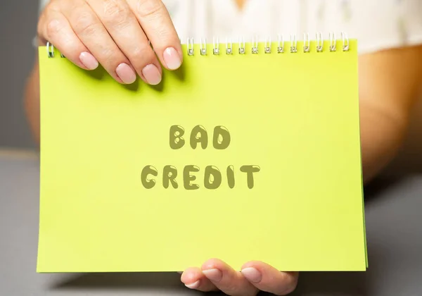 The inscription Bad credit in a notepad. Credit and loan concept. Business and finance. Woman's hand holding a notepad