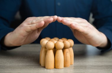 Bir adam çatı jesti ile bir grup insan figürü kapsıyor. Sigorta ve sosyal koruma kavramı. Hayat sigortası. Müşteri hizmetleri. İnsan kaynakları.