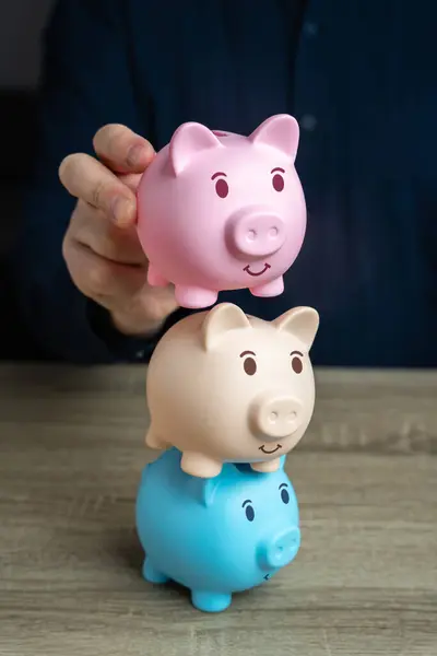 A businessman builds a tower from piggy banks. Savings and deposit banking. Multiple deposits. Healthy economy. Diversification of investments and savings. Banking. Good conditions from the bank.