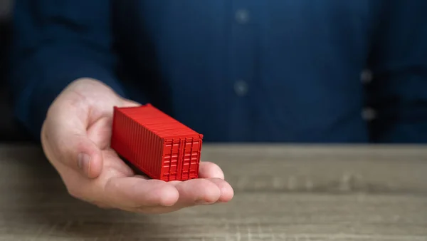 A man holds a red shipping containers in his hand. Cost savings due to bulk purchases or shared shipping expenses. Retailers and Suppliers. Transport operators. Customs authorities. Joint orders.